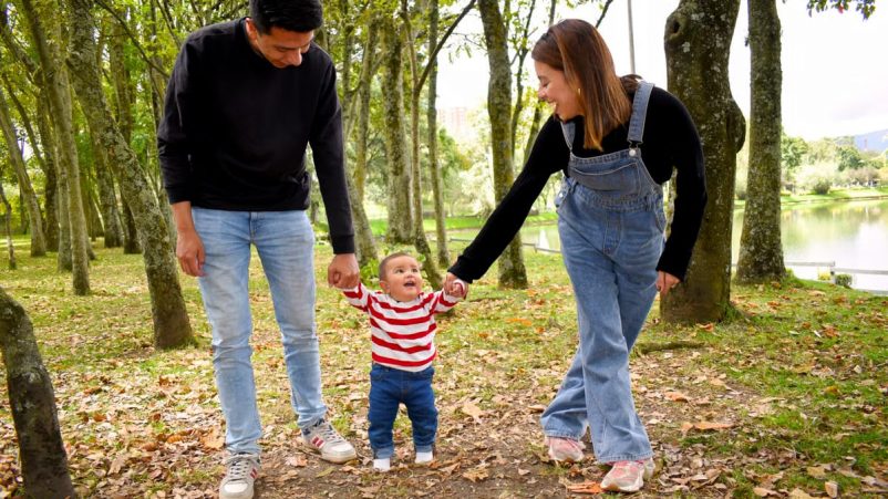 A joyful family enjoys a walk under lush green trees in the park.